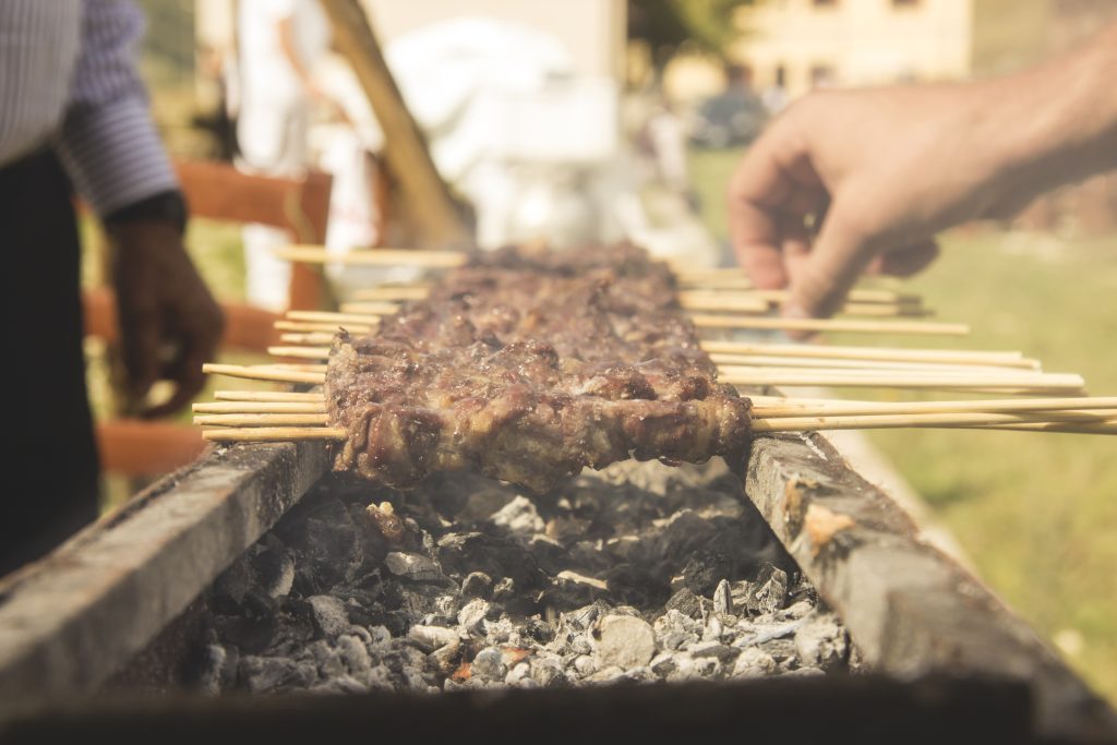 Arrosticini skewers on a charcoal grill.