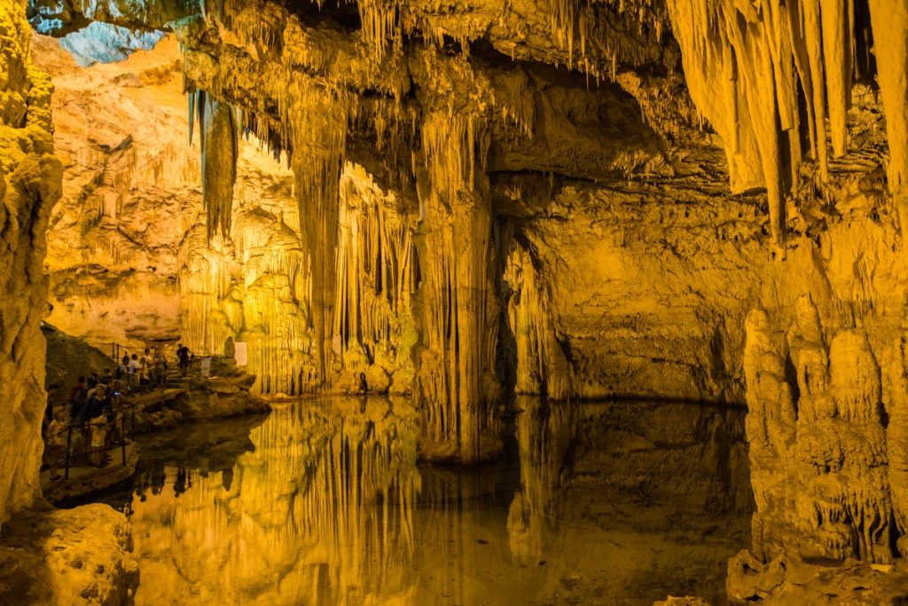 A visit of Grotta di Nettuno with dramatic stalactites, rock formations, and reflections over the underground lake is good reason to travel Sardinia.