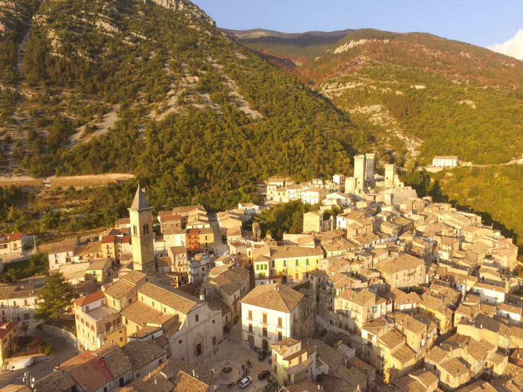 Abruzzo Travel Guide - Panoramic view of Pacentro nestled in the mountains at sunset, with warm light casting over historic rooftops.