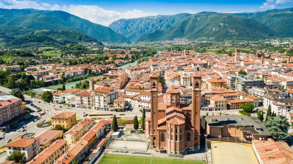 Aerial view of Bassano del Grappa with the Tempio Ossario prominently in the foreground and the town spread out beyond.