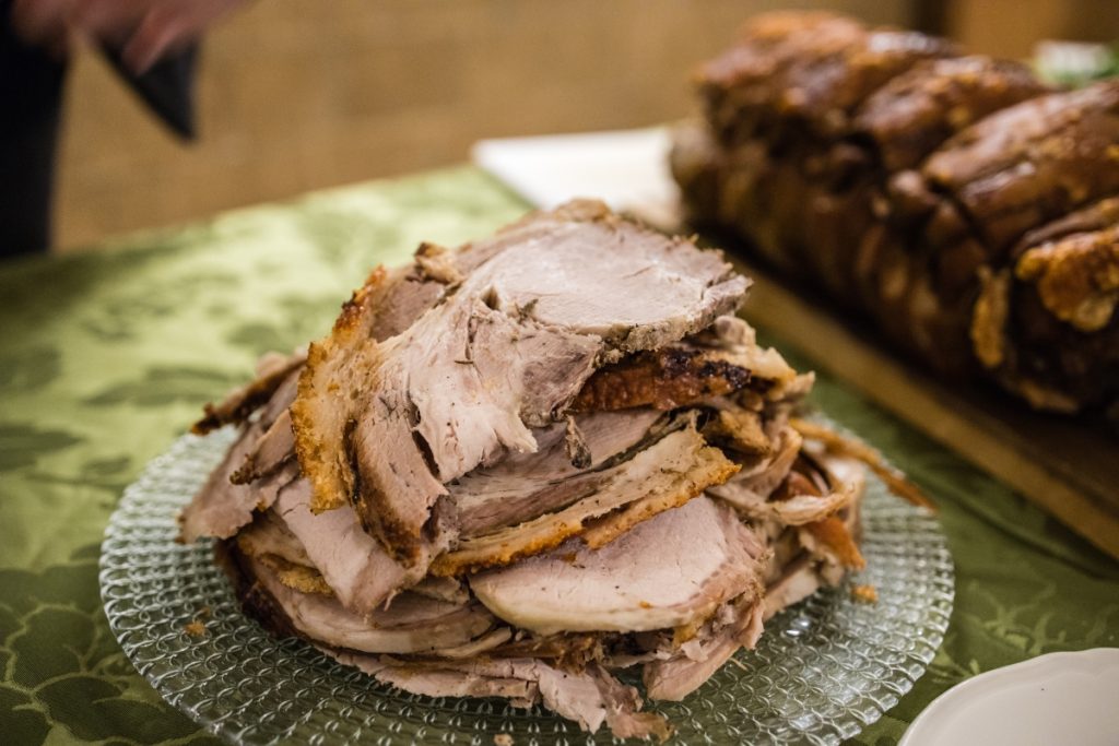 Sliced, herb‑crusted roasted porchetta from Castelli Romani with crispy skin and tender meat