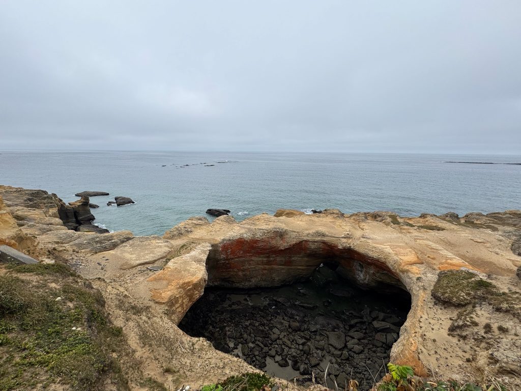 Devils Punchbowl rock formation on the Oregon Coast, where waves crash into a collapsed sea cave during a road trip stop